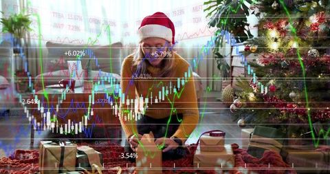 Wrapping christmas gift at home with stock market overlay, festive finance concept
