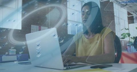 Mature woman typing on laptop in modern coworking space with digital data overlay and focus