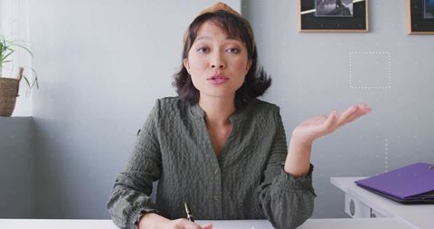 Asian Woman Writing and Speaking at Minimalist Office Workspace
