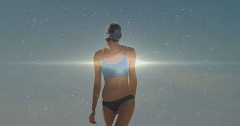 Sunlit beach woman walking in sporty bikini visor sunglasses cinematic lens flare grain