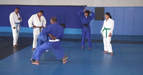 Judo Students Practicing Throws in Dojo on Blue Mats