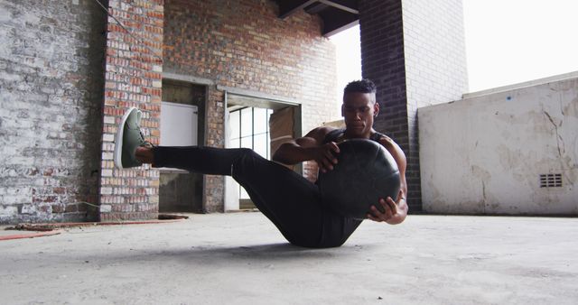 Man performing core workout with exercise ball in industrial setting - Download Free Stock Images Pikwizard.com