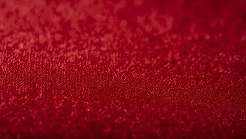 Macro red velvet glitter texture featuring bokeh highlights and sparkling granules