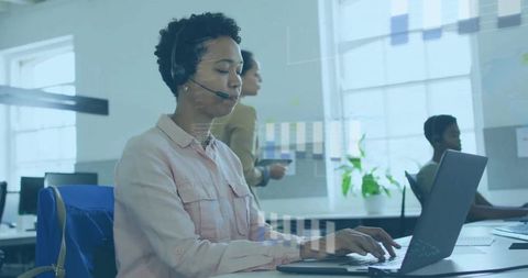 Customer Support Agent Typing on Laptop with Headset in Bright Open-Plan Workspace