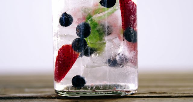 A close-up view of a refreshing drink with ice cubes, strawberries, and blueberries, with copy space. It's an inviting image for summer beverages or healthy drink options.