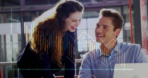Young professionals collaborating over laptop with data charts overlay in loft office