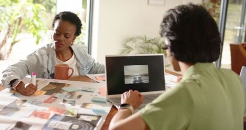 Multicultural team brainstorming and planning creative campaign with laptop sticky notes