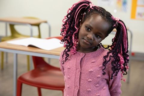 Thoughtful girl daydreaming in classroom with notebook