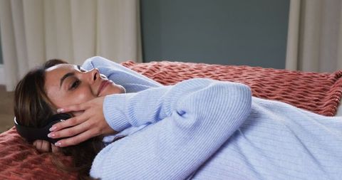 Woman Relaxing on Bed with Headphones in Cozy Home Environment
