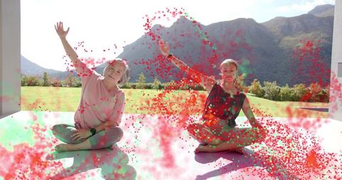 Mother and teen daughter waving tossing color powder on veranda with mountain view