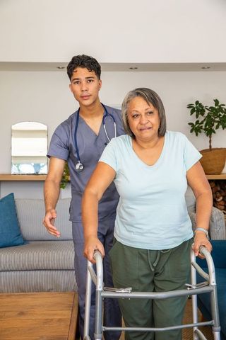 Senior Woman Using Walker with Caregiver Assistance at Home