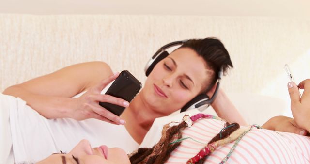 Two Women Relaxing on Bed Listening to Music - Download Free Stock Images Pikwizard.com