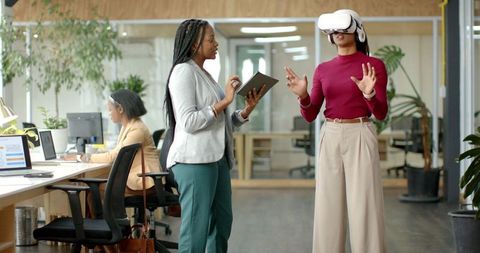 Diverse Female Team Testing VR Headset and Using Tablet for Workplace Training