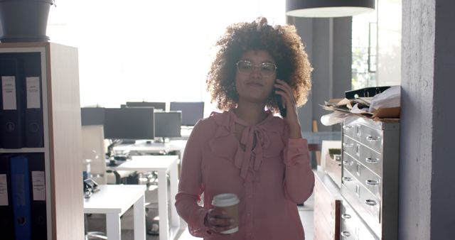 Businesswoman Talking on Phone While Holding Coffee in Office - Download Free Stock Images Pikwizard.com