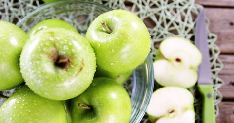 Fresh green apples in glass bowl with sliced apples