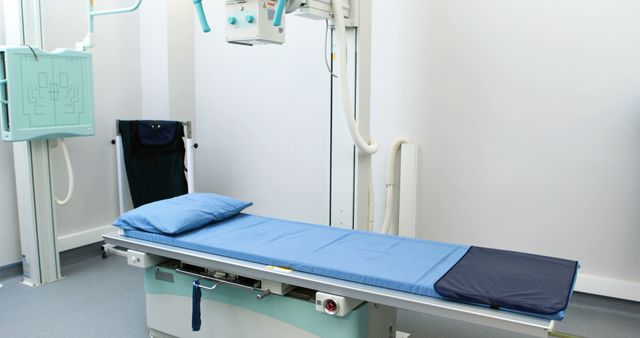 An empty hospital room equipped with a modern X-ray machine and a patient examination table, with copy space. The setting suggests a readiness for diagnostic medical procedures.