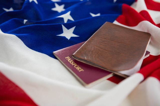 Close-up of a passport and visa placed on an American flag. Ideal for use in articles or advertisements related to travel, immigration, citizenship, and international tourism. Can also be used in patriotic contexts or discussions about nationality and identity.