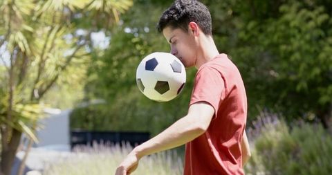 Young Man Practicing Football Skills in Sunny Garden