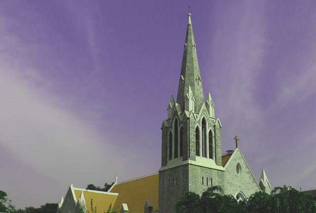 This dramatic image features a historic church with a prominent spire under a uniquely purple sky. Ideal for projects related to religion, architecture, historical landmarks, and gothic style structures. Suitable for articles, travel blogs, websites, and promotional materials focusing on cultural and spiritual topics.