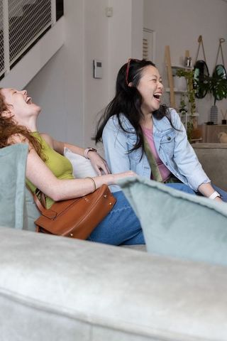 Friends laughing on cozy living room sofa sharing candid moment of joyful friendship