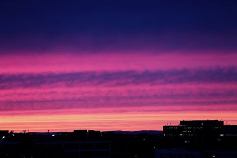 Glowing Pink and Purple Sunset Painting Sky Over City Skyline Silhouettes