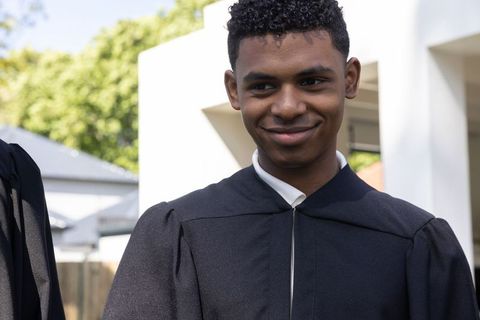 Young graduate smiling in academic robe portrait outdoors