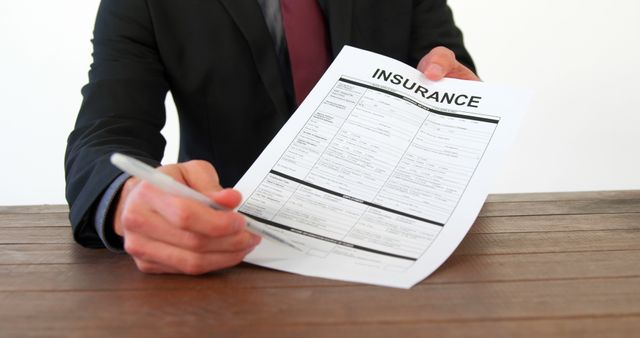 A Caucasian businessman is presenting an insurance form, with copy space. His focus on the document suggests a professional setting, emphasizing the importance of understanding insurance policies.