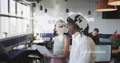 Professionals collaborating over laptop with world data overlay in modern coworking space