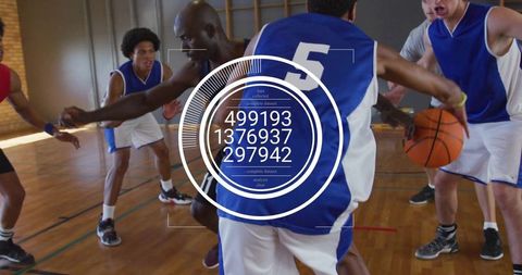Basketball Player Dribbling on Gym Court with Team Under Natural Light
