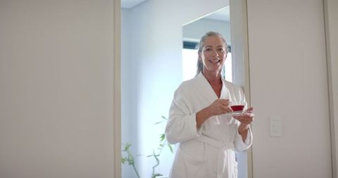 Smiling Mature Woman with Tea Enjoying Morning at Home in Bathrobe