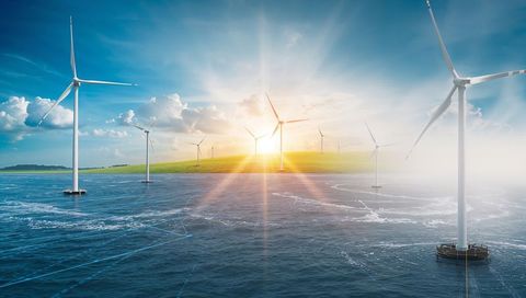 Offshore wind farm at sunrise with floating turbines and sun flare for clean energy
