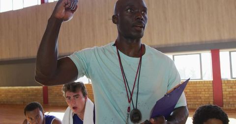 Determined coach motivating basketball team in gym training session