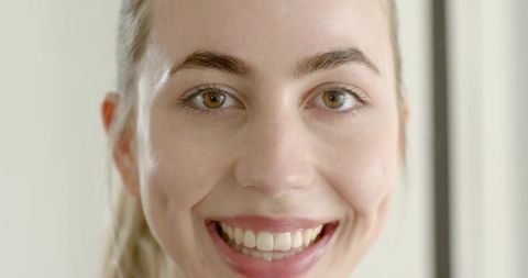 Closeup smiling young woman with hazel eyes and dimples, headshot with soft studio light