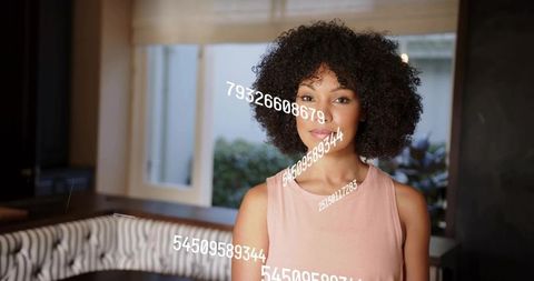 Young woman with curly hair standing in bright dining nook with floating numeric overlay