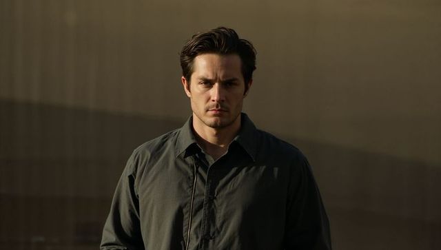 Serious man standing during golden hour urban portrait with moody facade and cinematic light