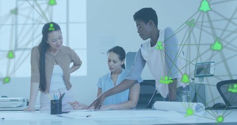 Team of female architects collaborating on blueprint with digital network overlay