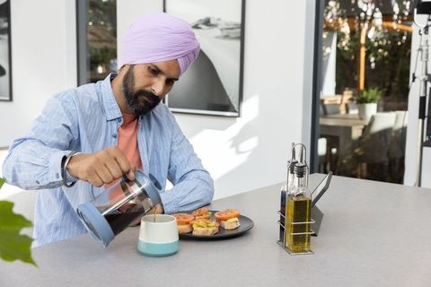Man with Turban Pouring Coffee Next to Avocado Sandwiches