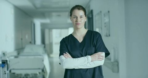 Confident Nurse in Hospital Corridor with Folded Arms in Navy Scrubs