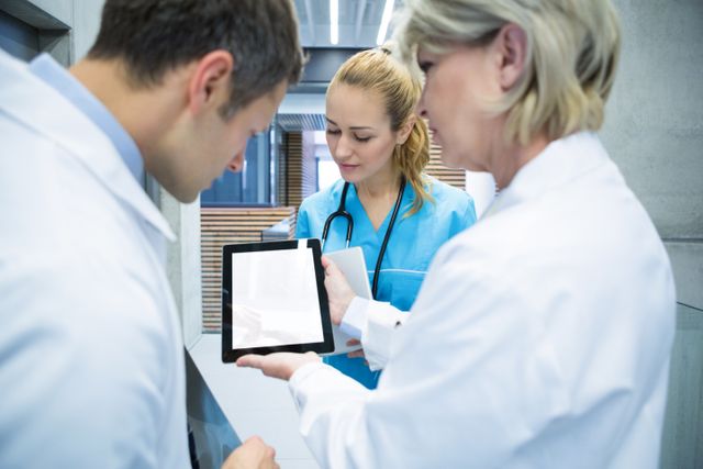 Medical team discussing over digital tablet in hospital