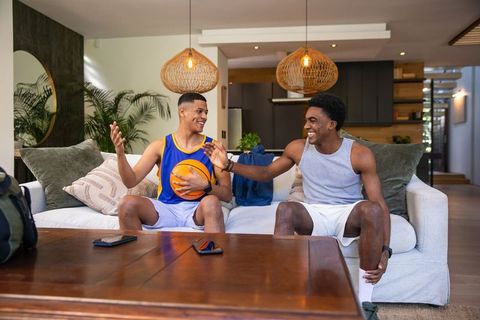Two Friends Relaxing and High-Fiving in Modern Living Room