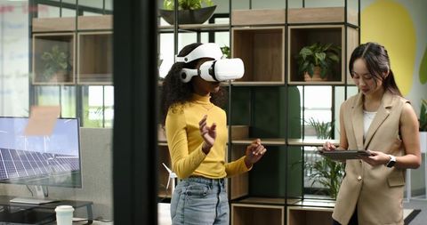 Women collaborating with vr and tablets in innovative office space