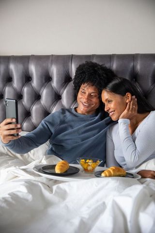 Diverse Couple Enjoying Breakfast in Bed Selfie Moment