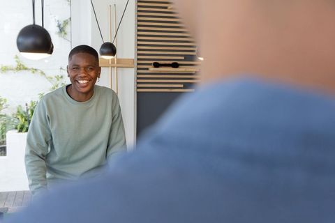 Smiling african american man conversing with colleague in modern office lounge