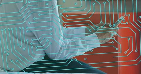 Businessman using smartphone with circuit board overlay on red lounge seat, tech concept