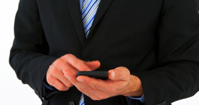 A middle-aged Caucasian businessman in a suit is focused on using his smartphone, with copy space. His engagement with the device suggests connectivity and the importance of mobile communication in professional settings.