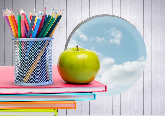 Apple and colour pencils on books against digitally generated sky background