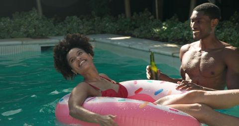 Joyful Couple Relaxing on Inflatable at Poolside
