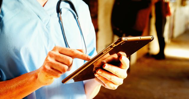 Healthcare professional in uniform using digital tablet for managing patient data. Demonstrates use of technology in medical field. Suitable for illustrating themes of modern healthcare, medical innovation, and digital patient records.