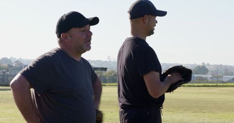 Two teammates standing on baseball field holding gloves preparing for community game