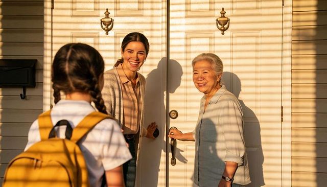 Multigenerational family greeting child at sunlit front door during golden hour